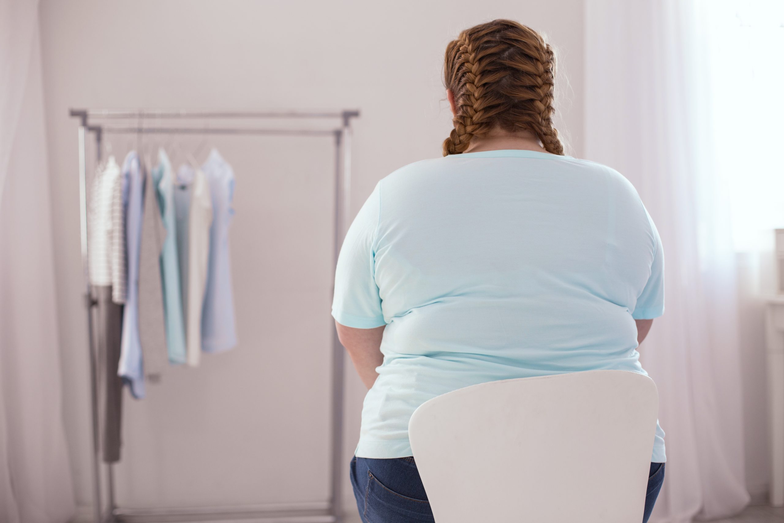 Obese woman sitting in a chair, looking at new clothes.
