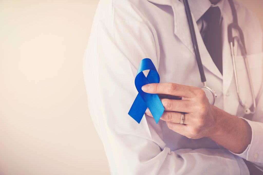 Doctor hands holding blue ribbon for diabetes and Colorectal Cancer Awareness