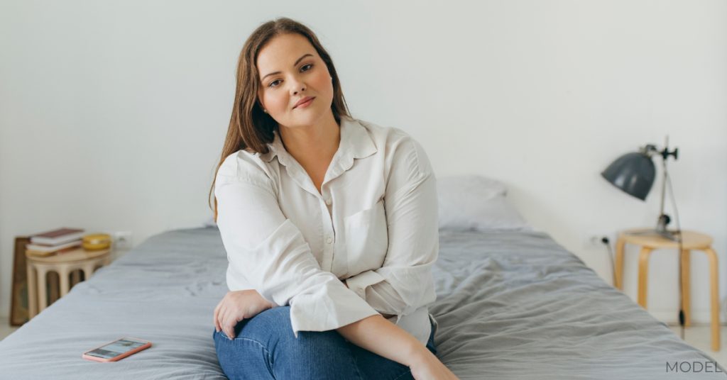 Portrait of a Confident Plus Size Woman Sitting on her Bed, Looking at Camera (model)